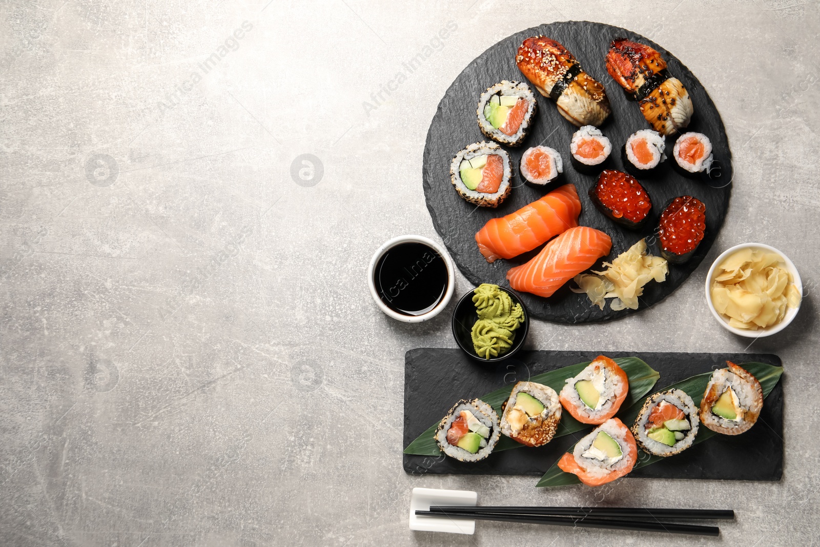 Photo of Different tasty sushi rolls on light grey table, flat lay. Space for text