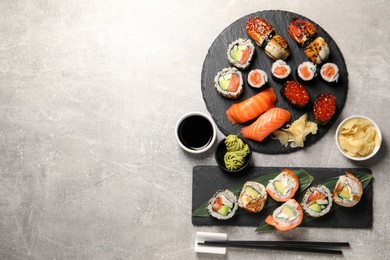 Different tasty sushi rolls on light grey table, flat lay. Space for text