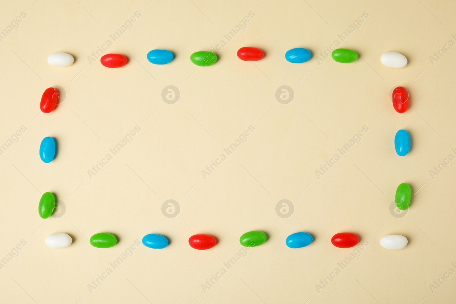 Photo of Frame of jelly beans on color background, top view. Space for text