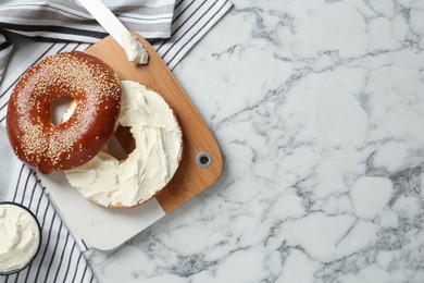 Photo of Delicious bagel with cream cheese on white marble table, flat lay. Space for text