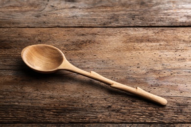 Photo of New clean empty spoon on wooden background