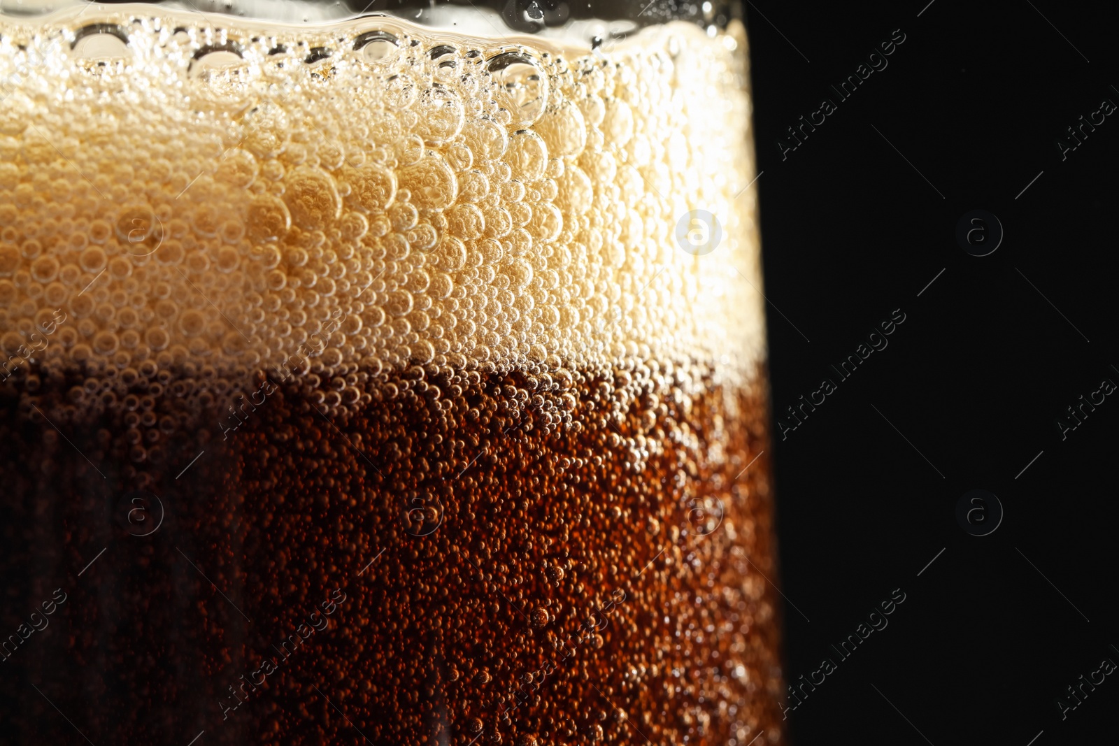 Photo of Glass of refreshing soda drink on black background, closeup