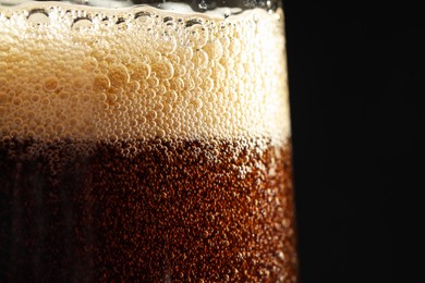 Glass of refreshing soda drink on black background, closeup
