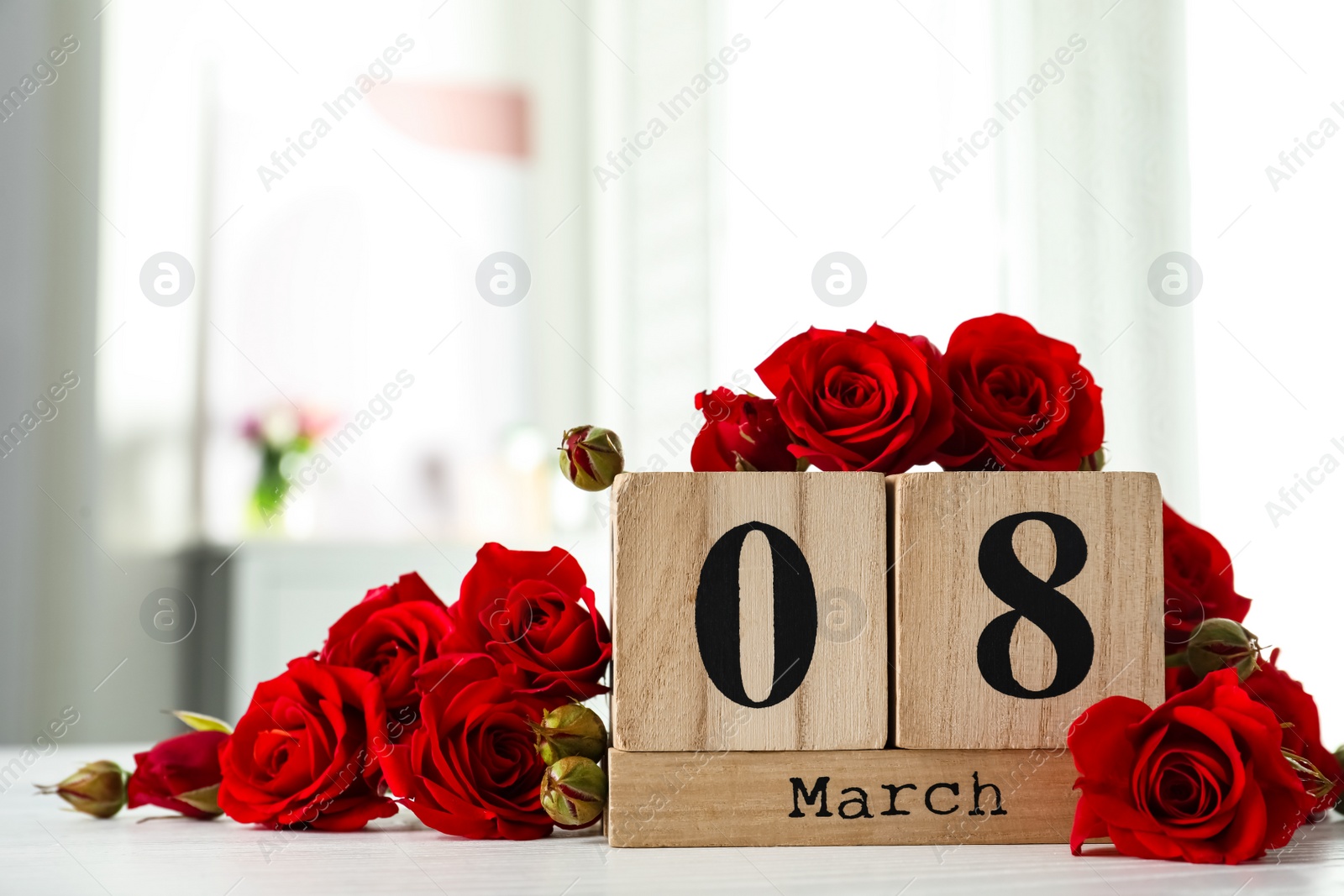 Photo of Wooden block calendar with date 8th of March and roses on table indoors, space for text. International Women's Day