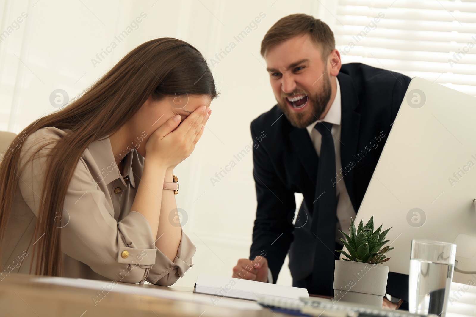 Photo of Boss screaming at employee in office. Toxic work environment