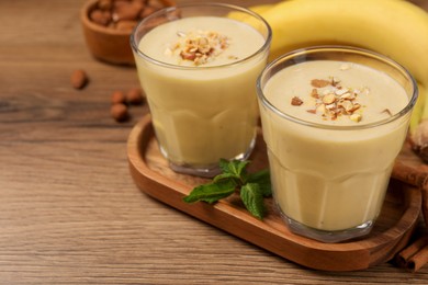 Photo of Tasty banana smoothie with almond and cinnamon on wooden table. Space for text