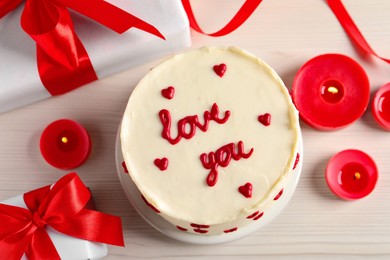 Photo of Bento cake with text Love You, candles and gift boxes on white wooden table, flat lay. St. Valentine's day surprise