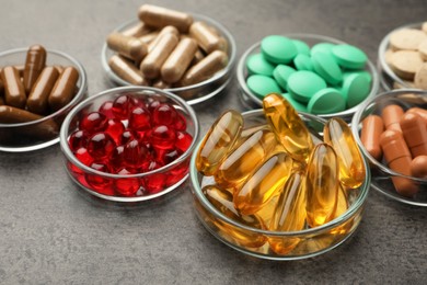 Different dietary supplements in glass bowls on grey table