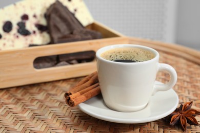 Photo of Delicious hot coffee with spices on wicker table. Space for text