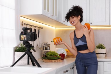 Smiling food blogger explaining something while recording video in kitchen