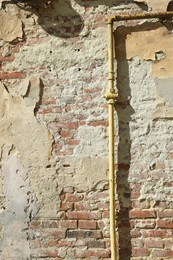 Photo of Yellow gas pipe on old brick wall outdoors