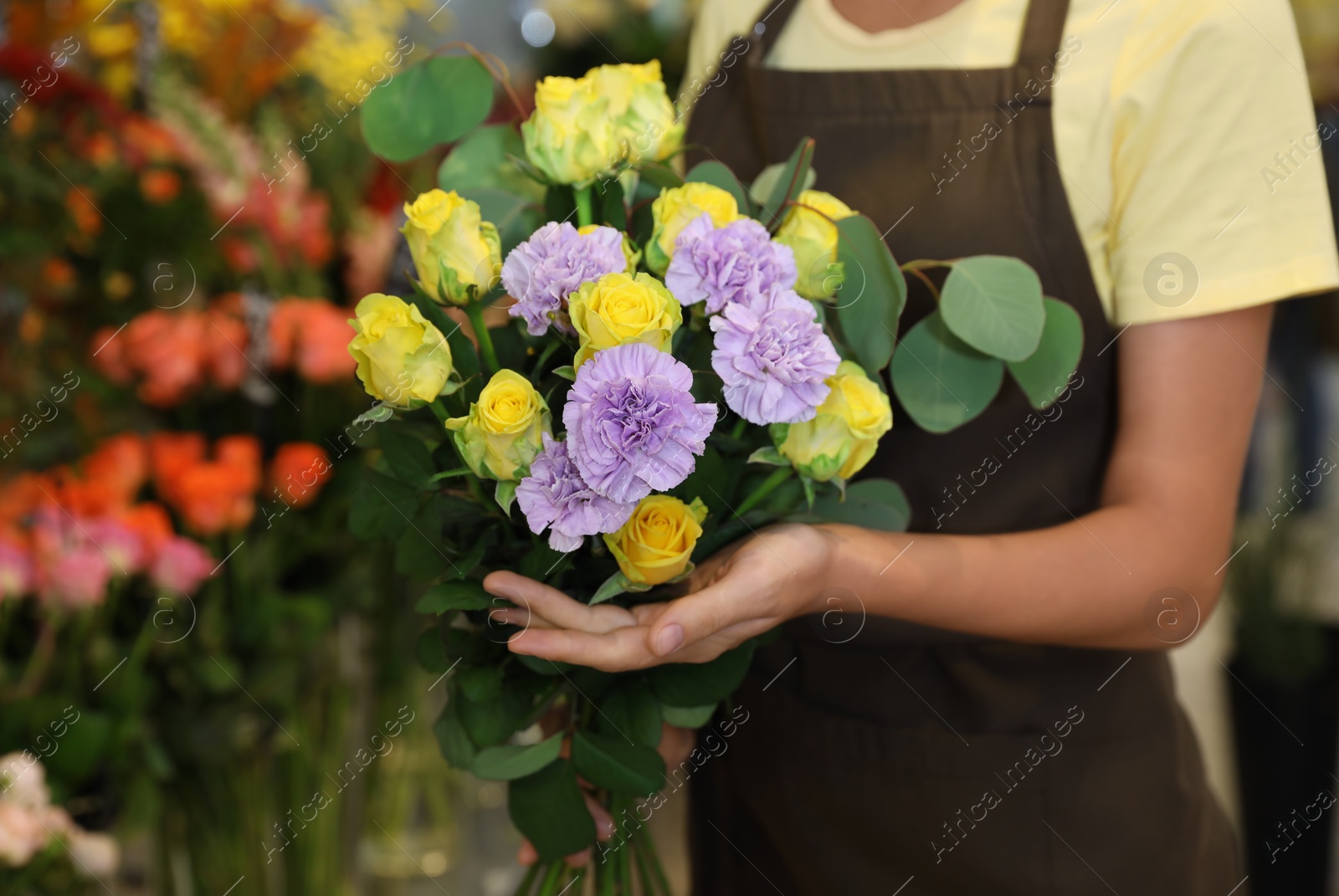 Photo of Female florist holding beautiful bouquet in flower shop, closeup