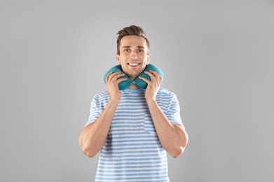 Photo of Happy young man with neck pillow on gray background
