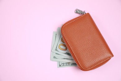 Stylish brown leather purse with dollar banknotes on pink background, flat lay. Space for text