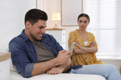 Photo of Man preferring smartphone over spending time with his girlfriend at home. Jealousy in relationship