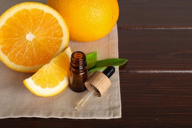 Photo of Bottle of essential oil with oranges and mint on wooden table. Space for text