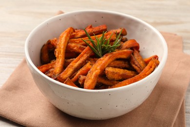 Bowl with sweet potato fries and rosemary on wooden table, closeup