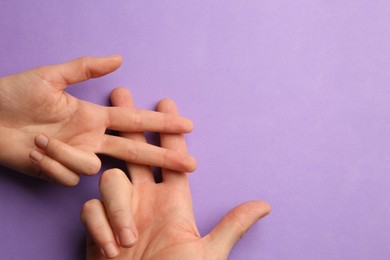 Photo of Man and woman making hashtag symbol with their hands on violet background, top view. Space for text