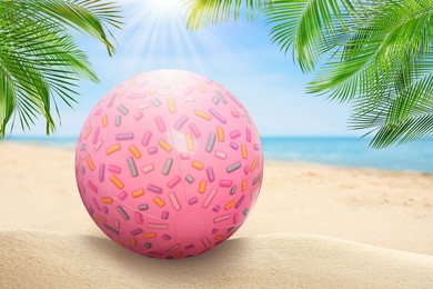 Image of Pink beach ball on sandy coast near sea