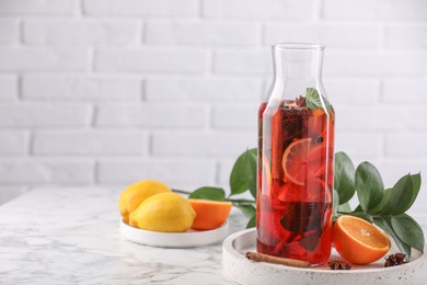Photo of Delicious punch drink in bottle and ingredients on white marble table. Space for text