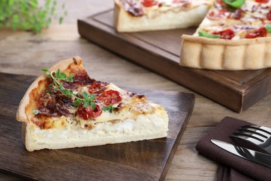 Photo of Piece of delicious homemade quiche with prosciutto, tomatoes and microgreens served on wooden table