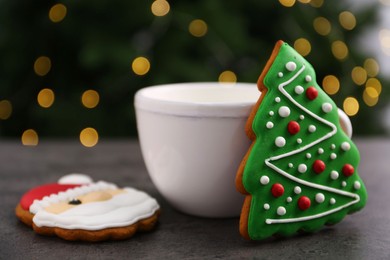 Photo of Decorated cookies and hot drink on grey table against blurred Christmas lights