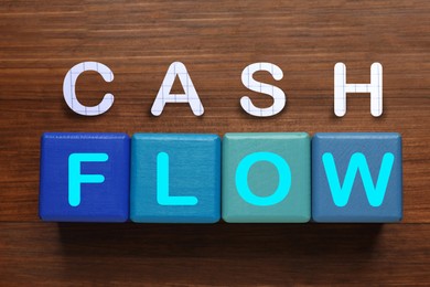 Image of Phrase Cash Flow made with letters and blue cubes on wooden background, flat lay