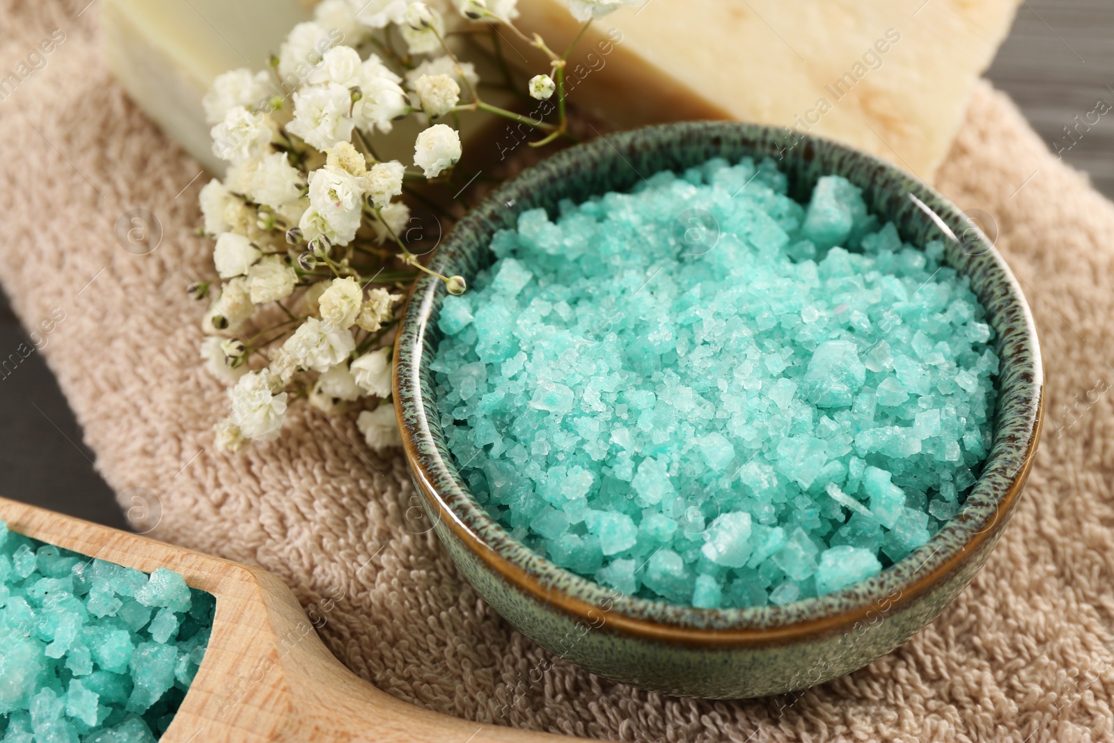 Photo of Aromatic sea salt and beautiful flowers on grey table, closeup