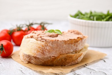 Photo of Delicious liverwurst sandwich with basil on white textured table, closeup