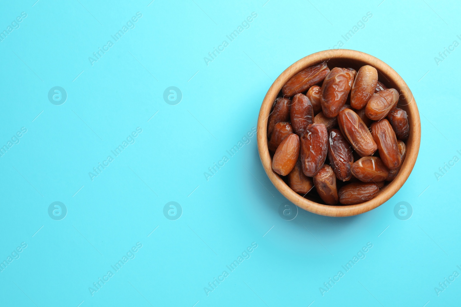 Photo of Bowl with sweet dried date fruits on color background, top view. Space for text