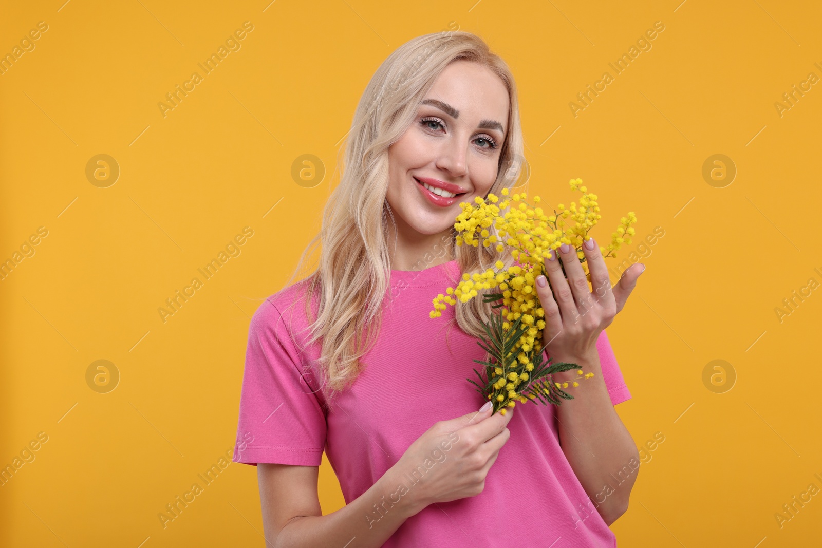 Photo of Happy young woman with beautiful bouquet on orange background