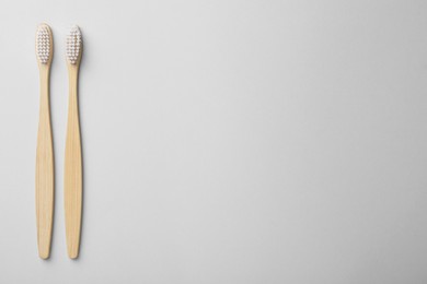Bamboo toothbrushes on light background, flat lay. Space for text
