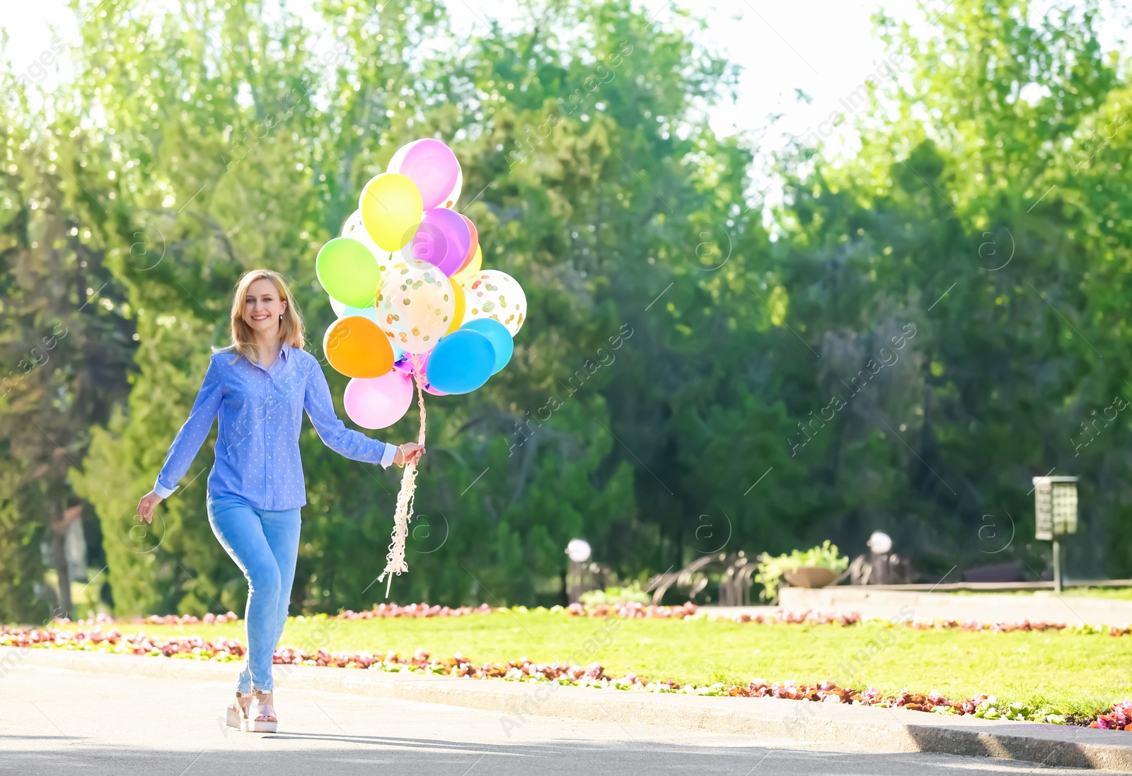 Photo of Young woman with colorful balloons in park on sunny day