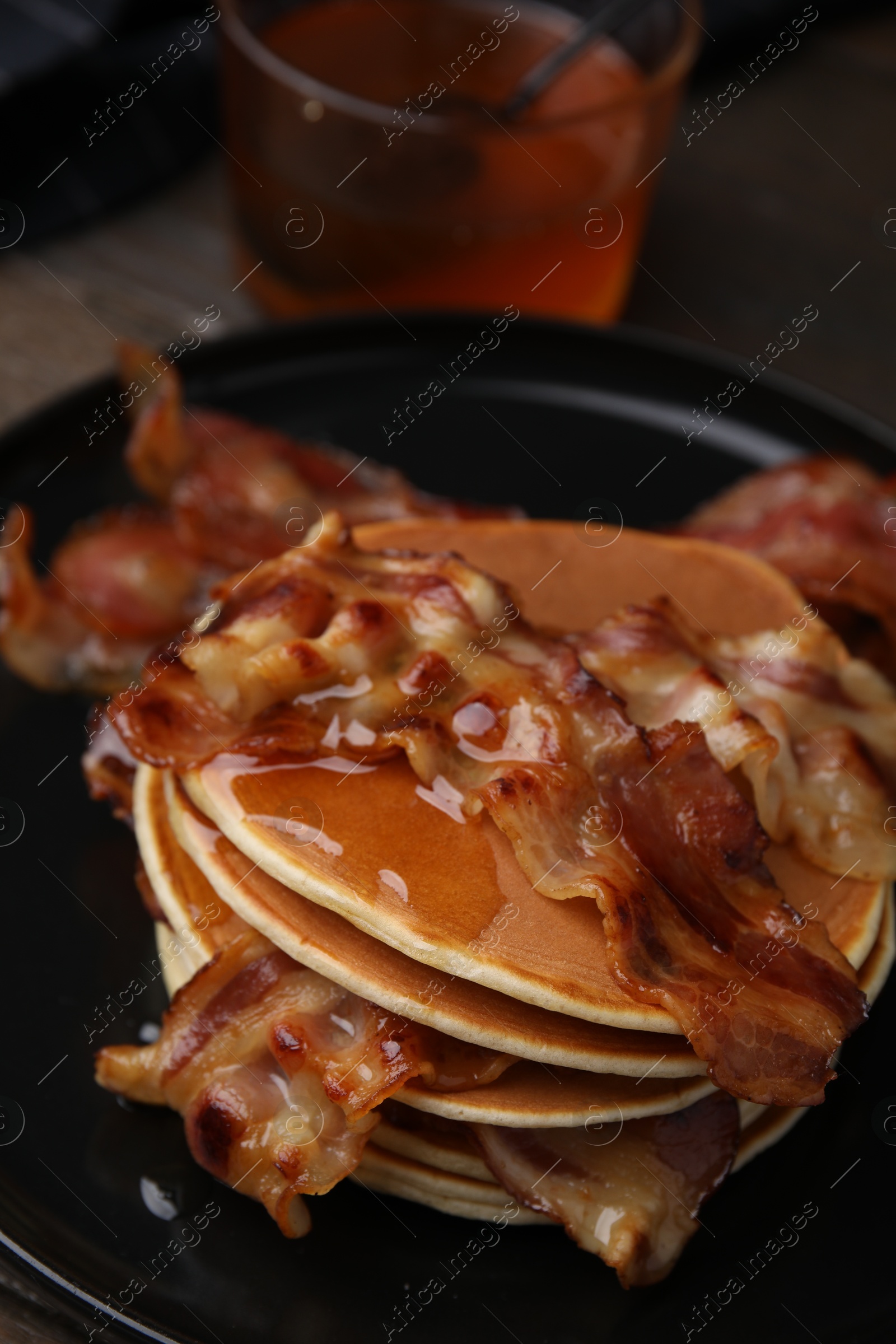 Photo of Delicious pancakes with fried bacon served on wooden table, closeup