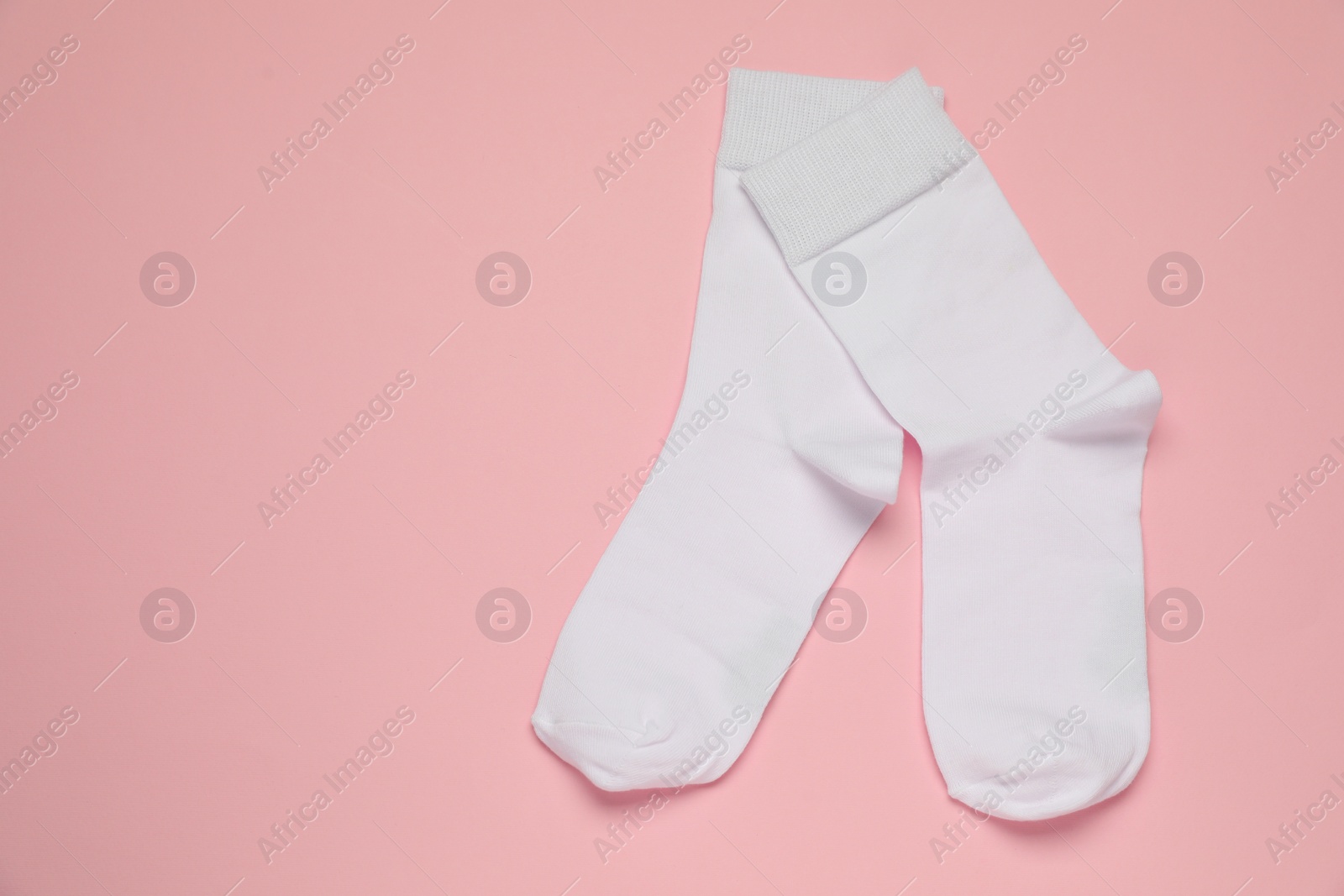 Photo of White socks on pink background, flat lay. Space for text