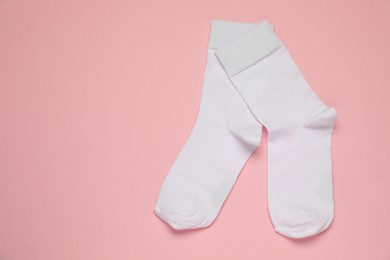 Photo of White socks on pink background, flat lay. Space for text