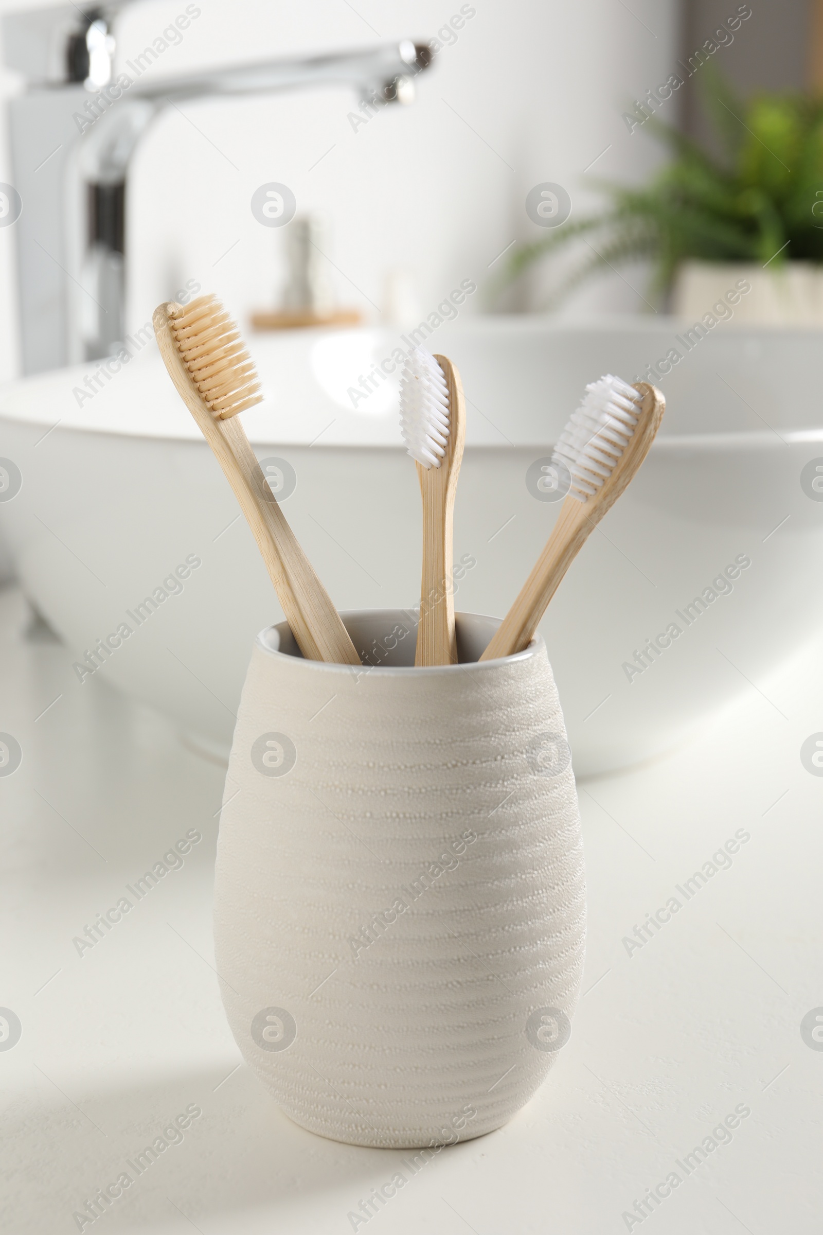 Photo of Bamboo toothbrushes on white countertop in bathroom