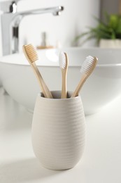 Bamboo toothbrushes on white countertop in bathroom