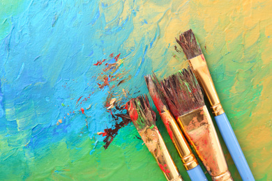 Photo of Abstract colorful artwork and brushes, top view