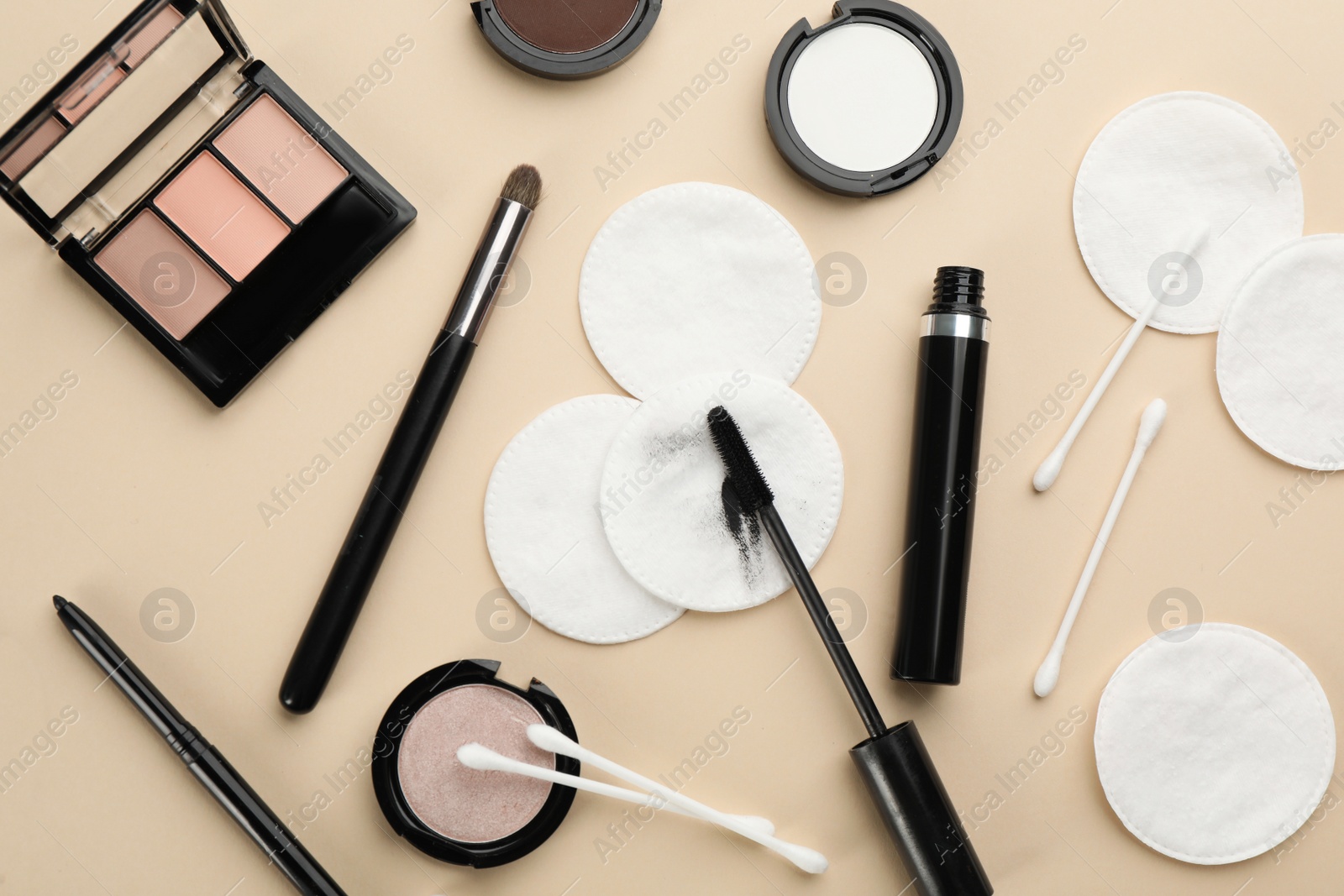 Photo of Cotton pads, swabs and cosmetic products on beige background, flat lay