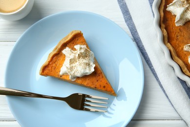Photo of Delicious pumpkin pie with whipped cream and fork on white wooden table, flat lay