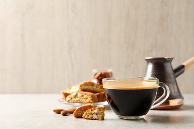 Photo of Tasty cantucci and cup of aromatic coffee on light grey table, space for text. Traditional Italian almond biscuits