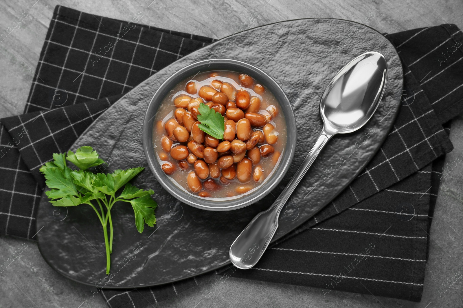 Photo of Tasty canned kidney beans with parsley served on grey table, top view