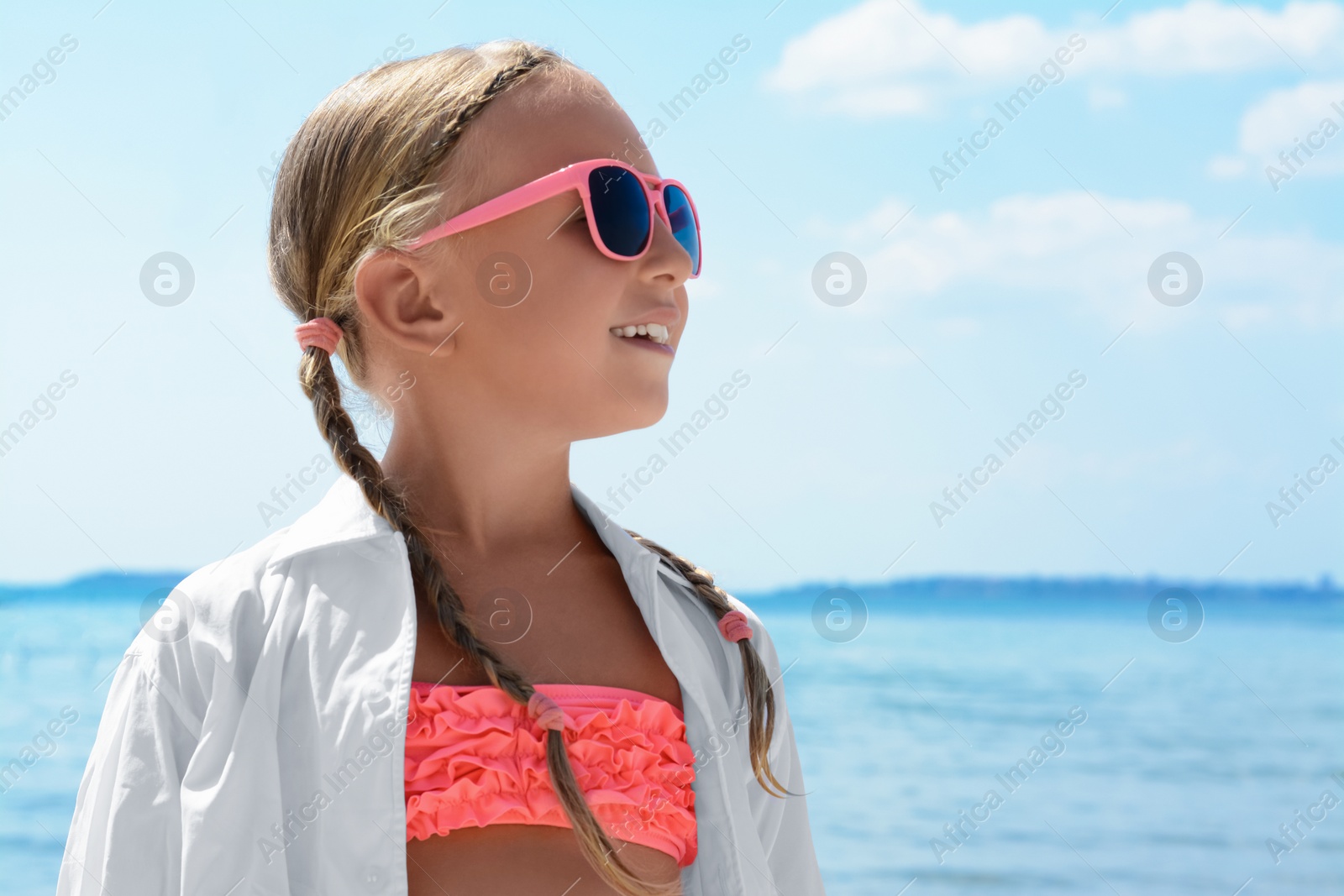 Photo of Little girl wearing sunglasses at beach on sunny day. Space for text