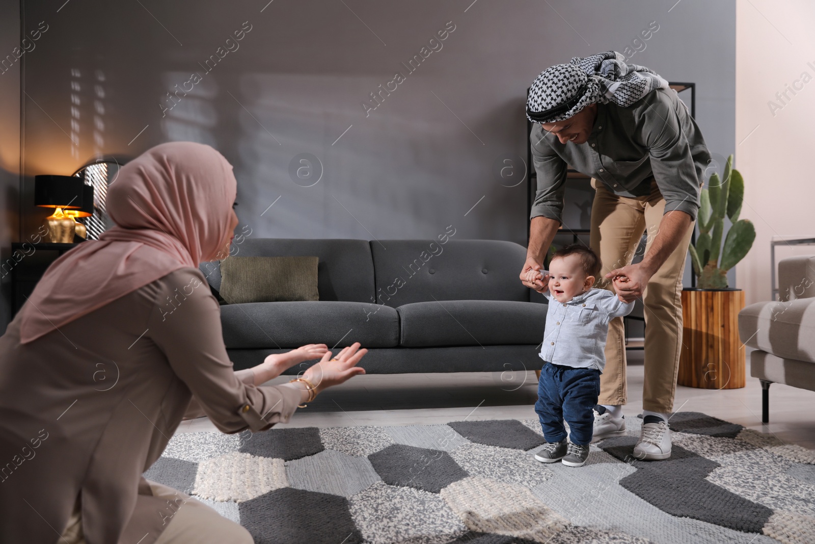 Photo of Happy Muslim family with little son in living room