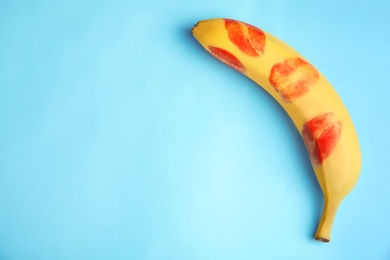 Photo of Top view of fresh banana with red lipstick marks on blue background, space for text. Oral sex concept