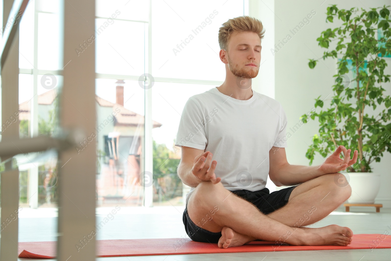 Photo of Handsome young man practicing zen yoga indoors