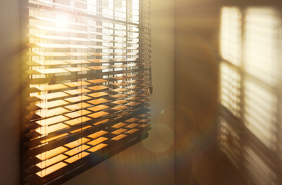 Image of Sun shining through window blinds in room