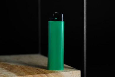 Photo of Stylish small pocket lighter on wooden table against black background