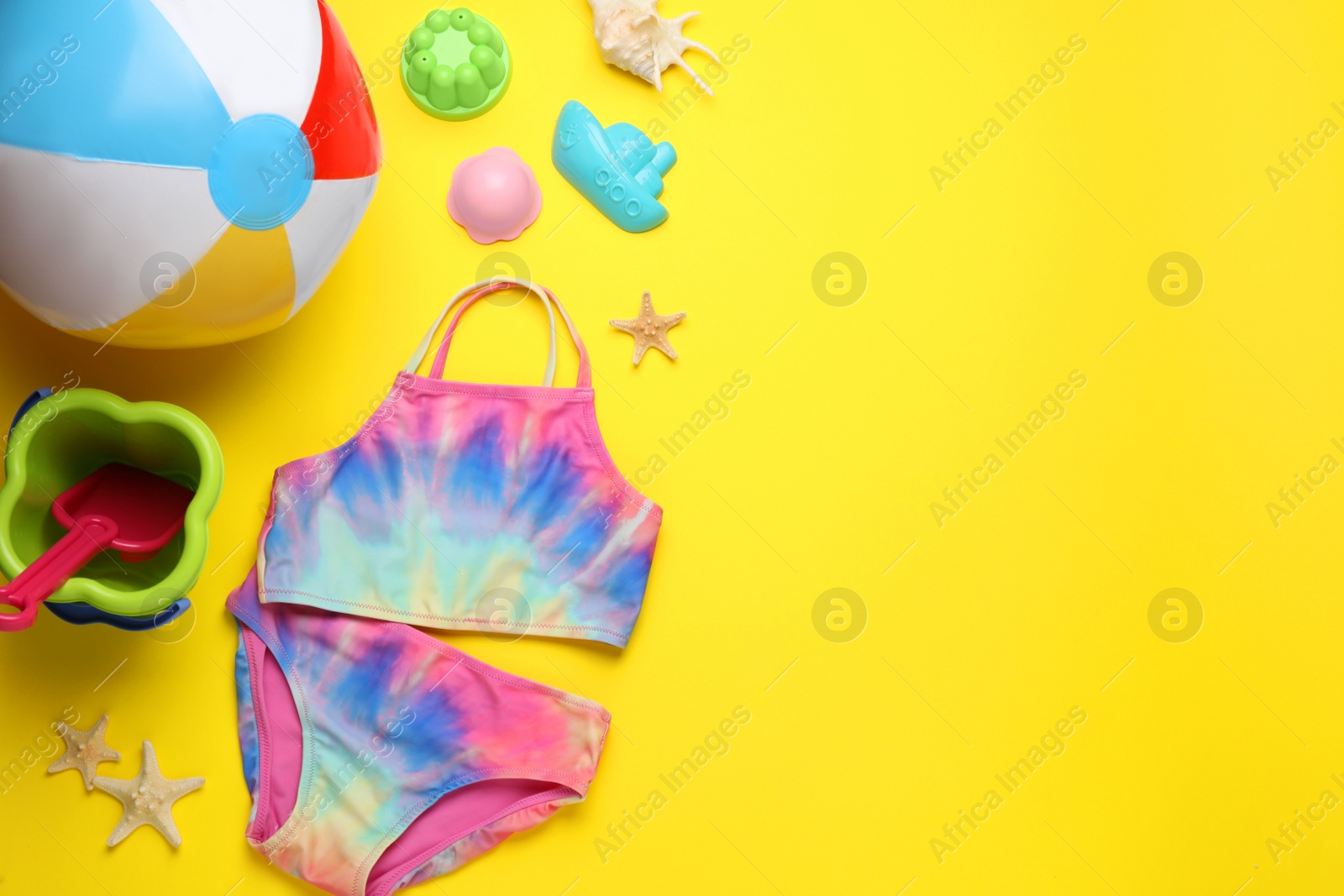 Photo of Flat lay composition with beach ball and sand toys on yellow background, space for text